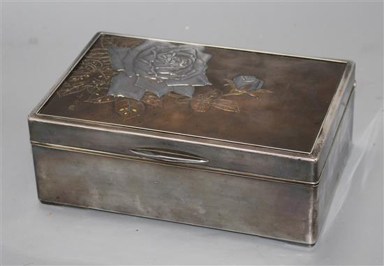 A Japanese silver, copper and gold cigarette box, Meiji period, decorated with a panel of roses, signed, 22 x 14.5cm, height 8cm